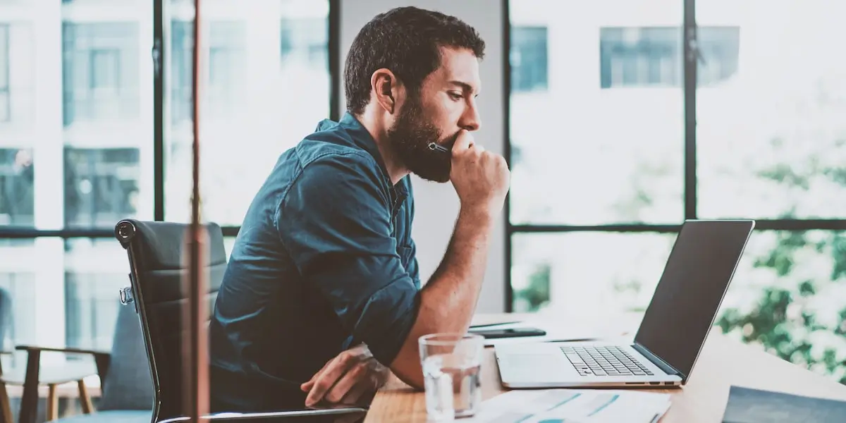 A coder earning a machine learning engineer salary sits at his laptop in an office.