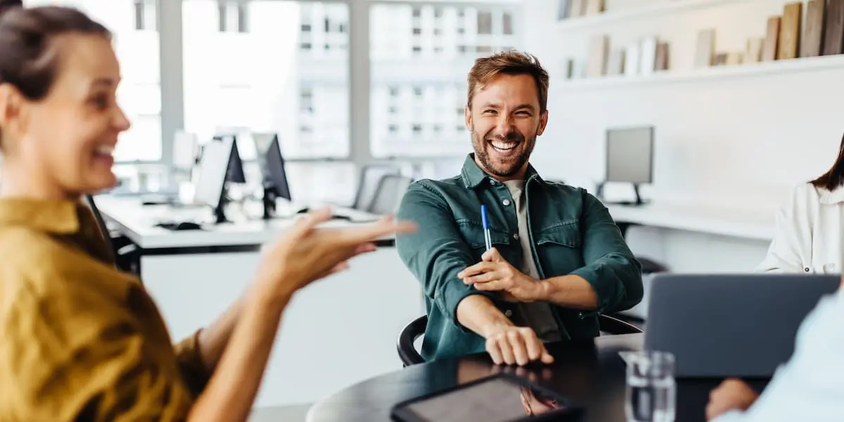 An employee who made a career change at 30 sitting at a table with his colleagues laughing