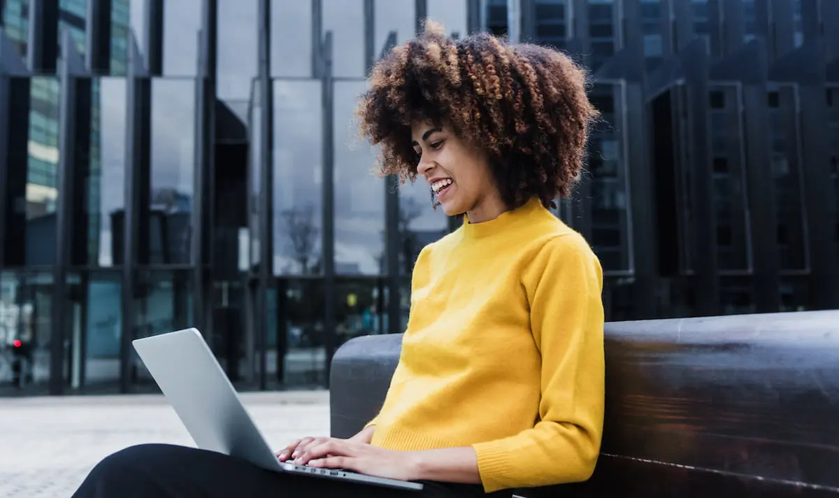 A Black woman earning a software engineer salary in New York sits on her laptop working.