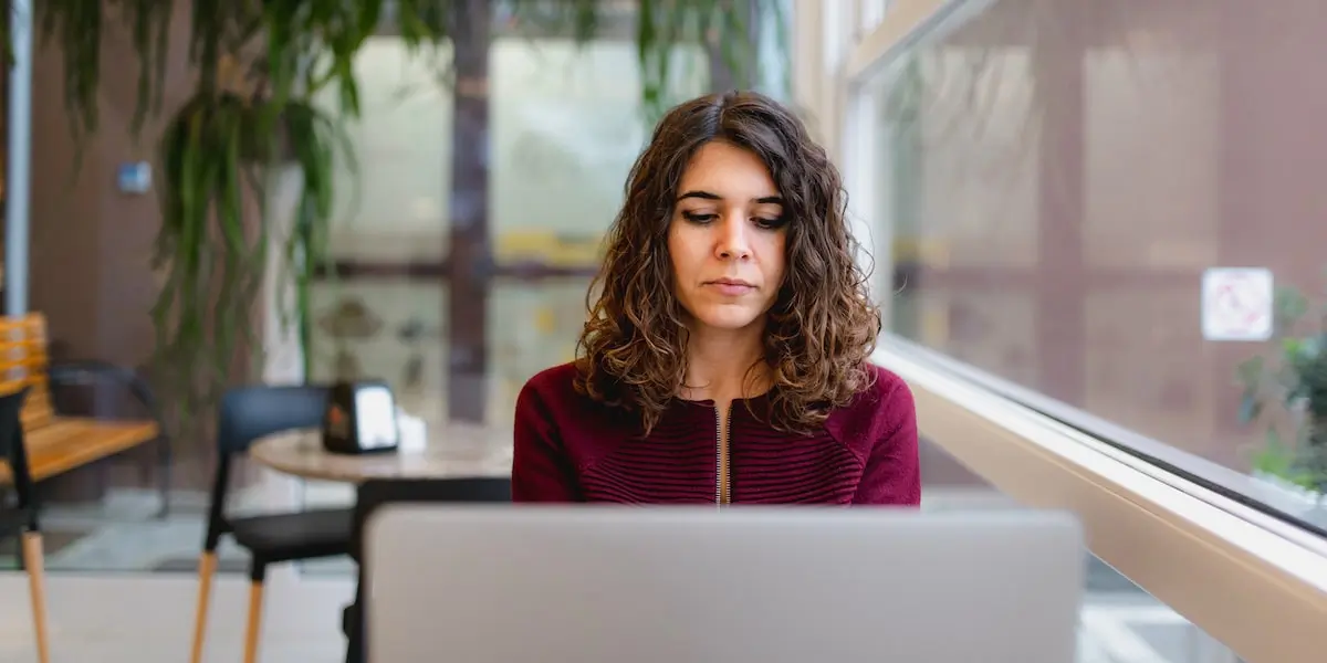 A senior product manager sits at a laptop in a cafe working.