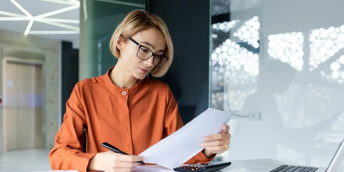 Neatly dressed employee works at desk reading up on whether ai is taking over jobs