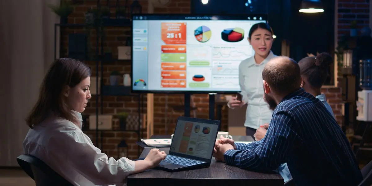 A marketer presents the results of data visualization courses to her colleagues on a screen.