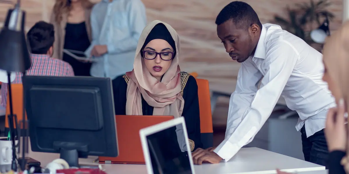 A growth product manager talks to their colleague in a busy office.