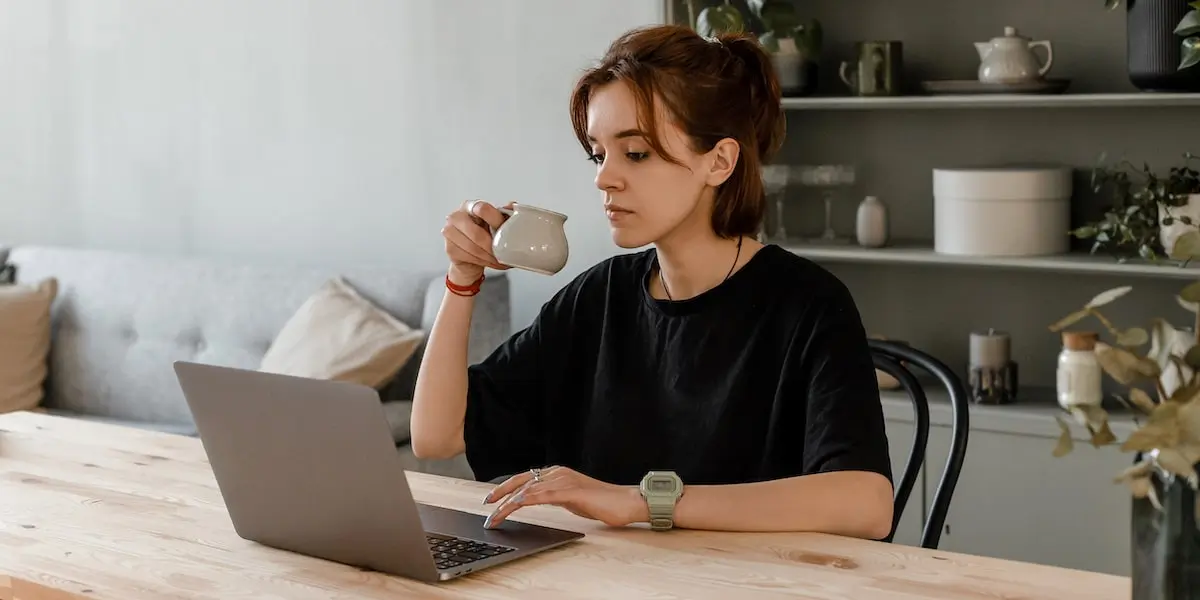 A woman sits at a table at her laptop studying what is machine learning.