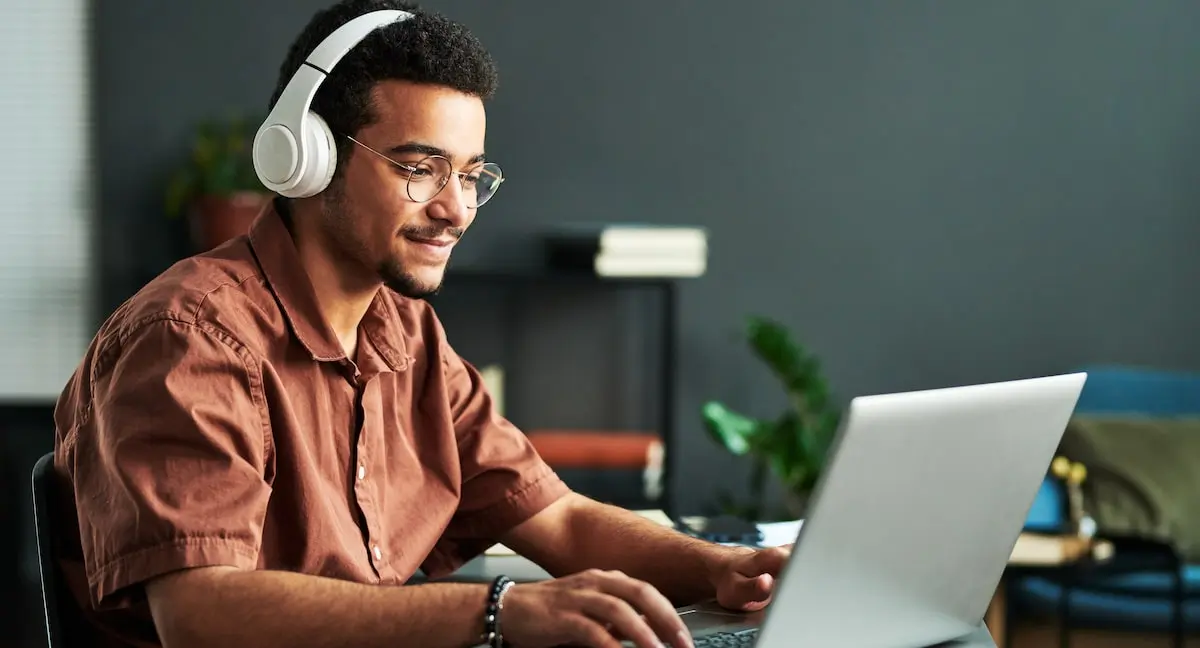 A similing coder tries to learn TypeScript on his laptop at home.