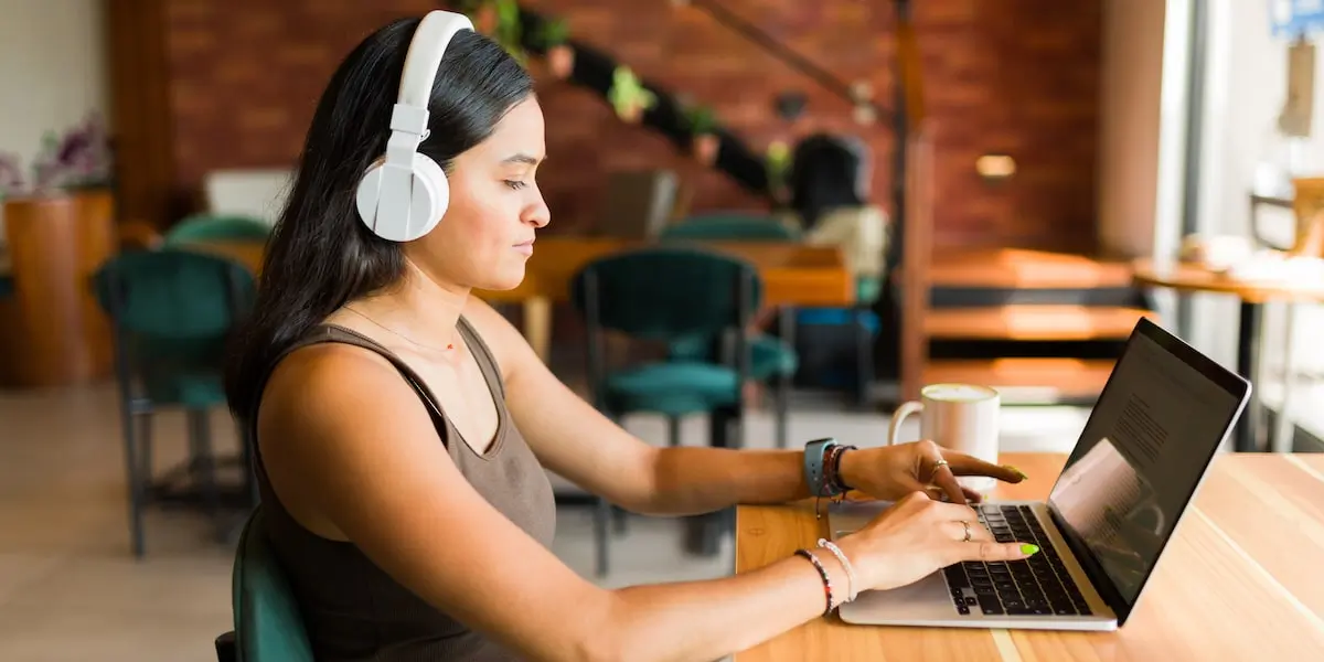 An AI engineer works away on her laptop in a bright cafe.