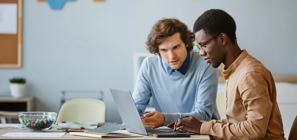 two male designers sit at a laptop using chatGPT for UI design