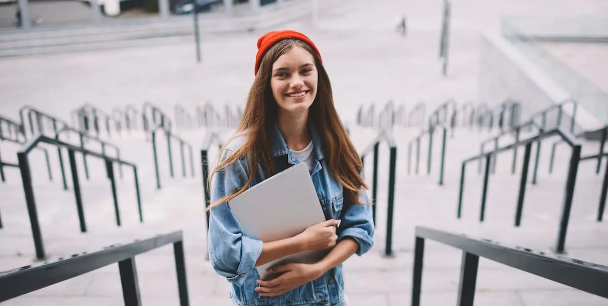 A UX designer in berlin standing on steps with her laptop in hand