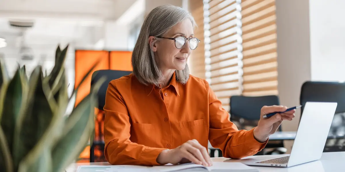 A elderly woman sits at a desk using ChatGPT to write an AI cover letter