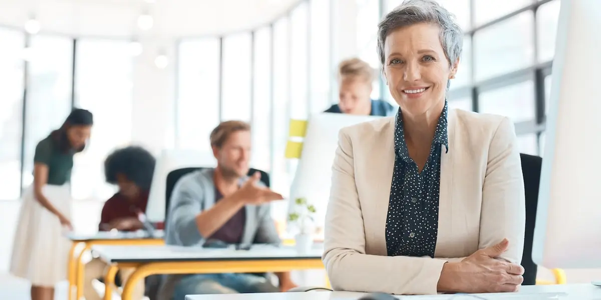 A product manager with a product management cheat sheet smiles at her desk.