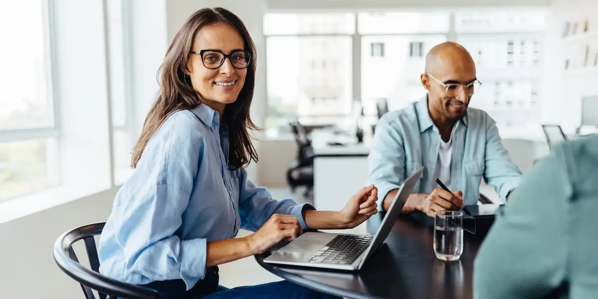 two digital marketers, a male and a female, sit at a desk using their laptops to use chatGPT for marketing