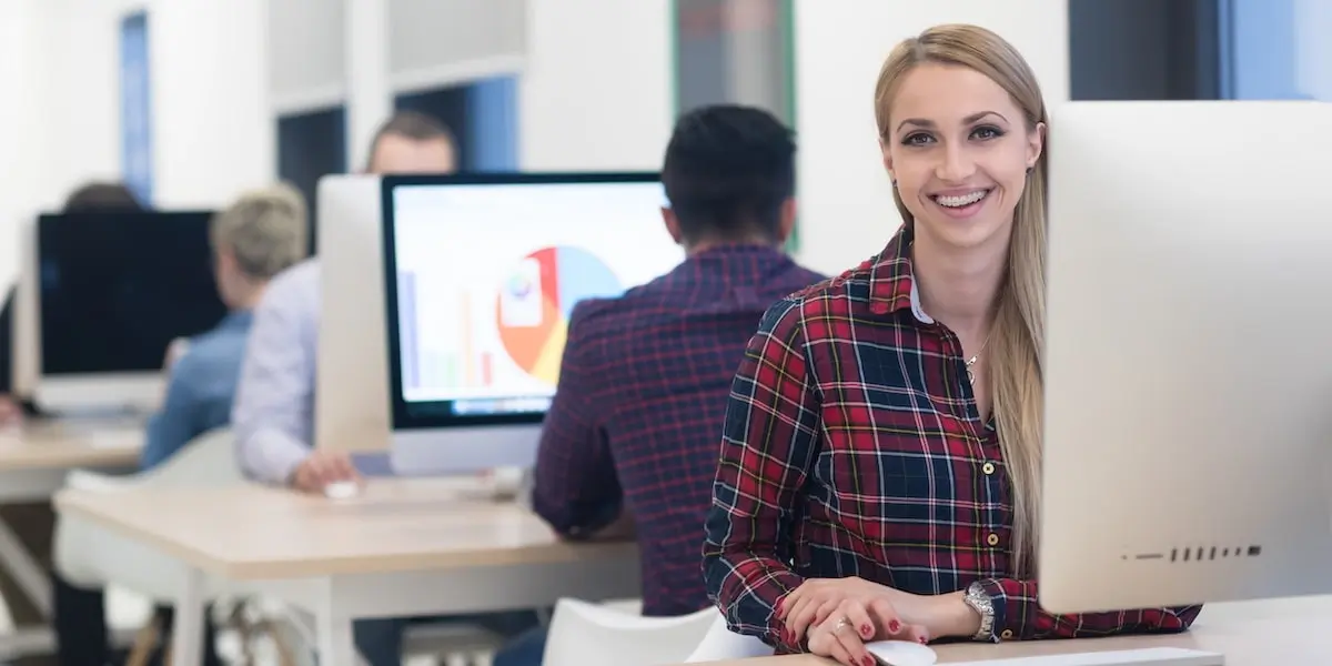 Colleagues doing machine learning jobs sit at desktops in a bright office.