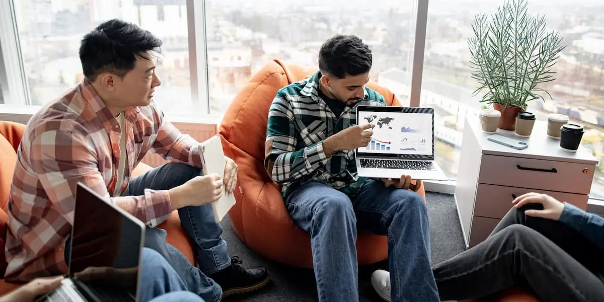 Two data analysts comparing looker vs tableau tools on a laptop in an office.