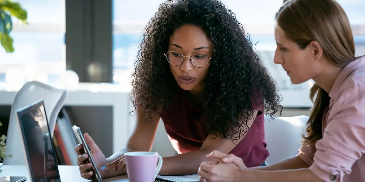 Two female SEO managers work at their laptop to integrate UX design into into their website SEO efforts