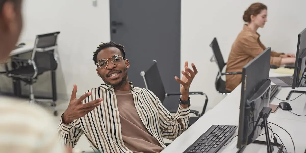 A man discusses AI for product managers to his colleague in an office.