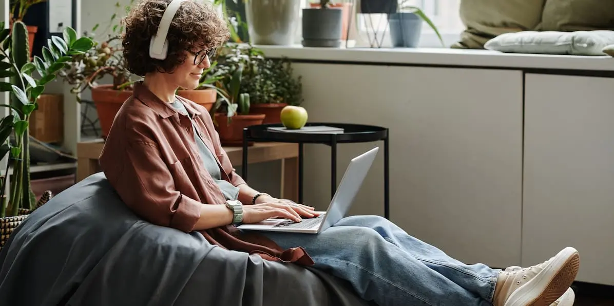 A woman sits in a bean bag working on AI project ideas on a laptop.