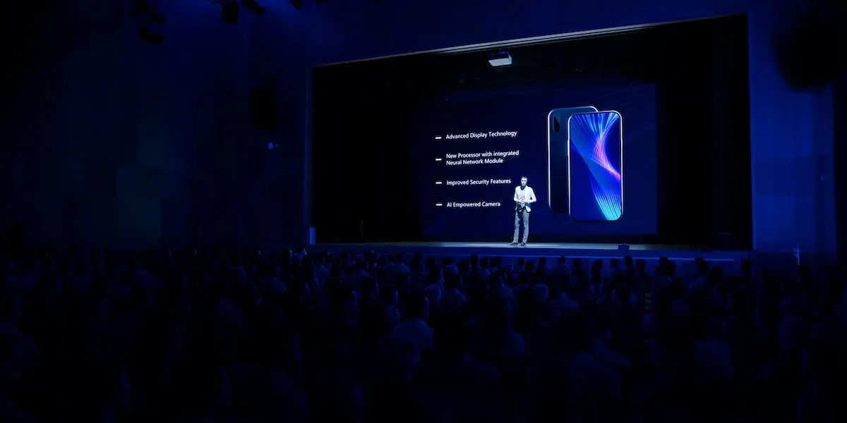 A man stands on a huge stage demonstrating how to launch a product.