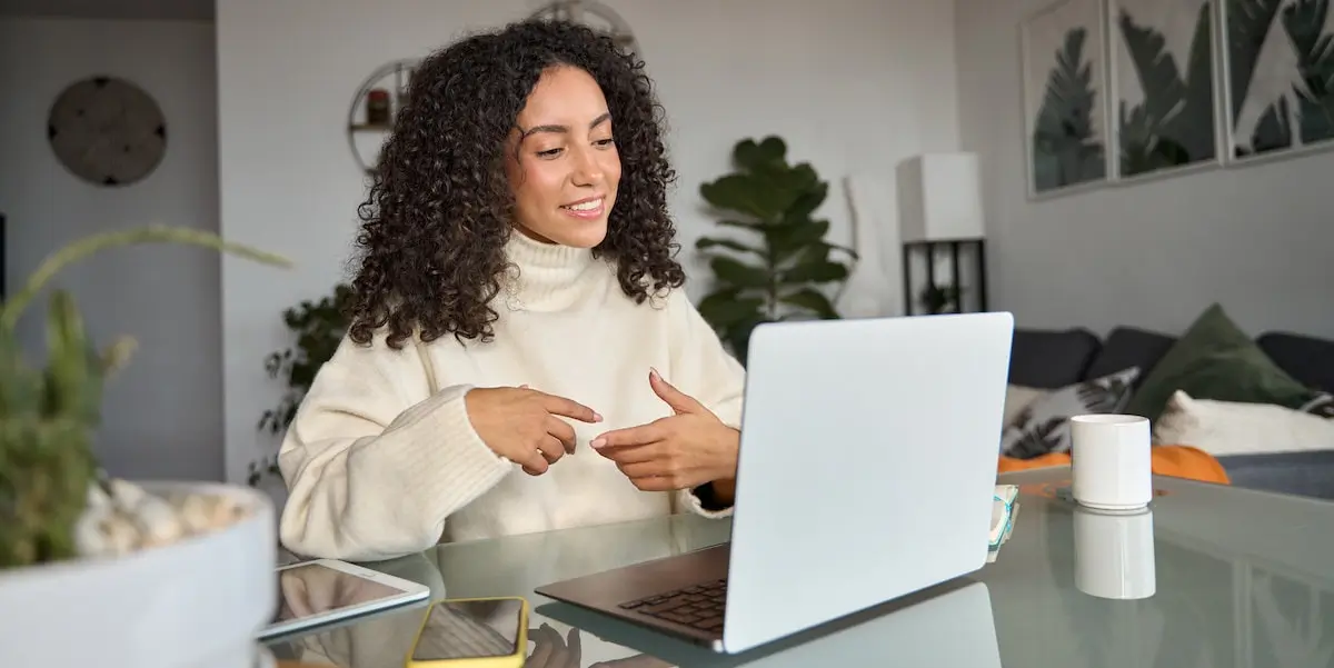 A young woman sits at her laptop having a job interview asking questions