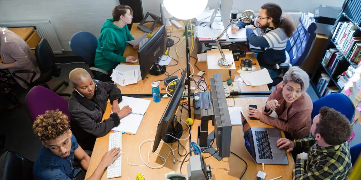 Various types of product managers working at a desk of computers.