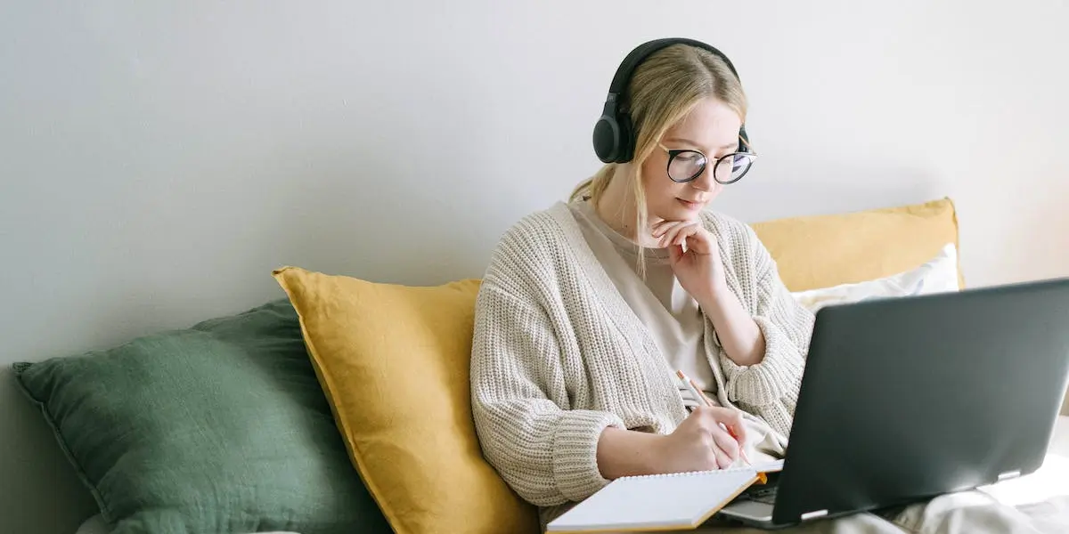 A woman takes product design bootcamps on her laptop in bed.