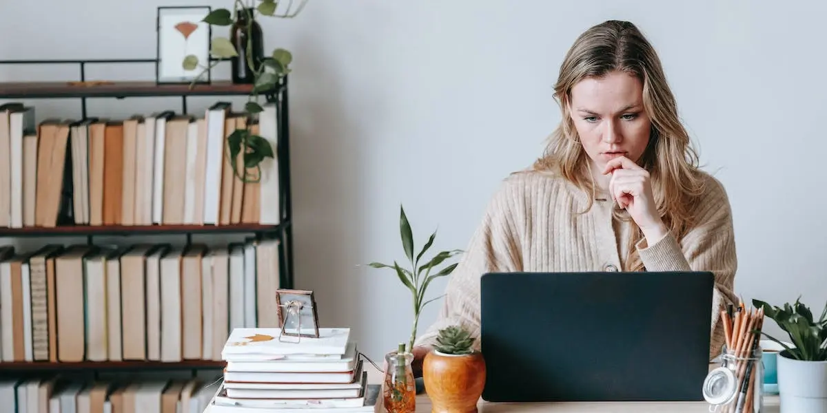 A young woman sits at her laptop thinking during the product design process