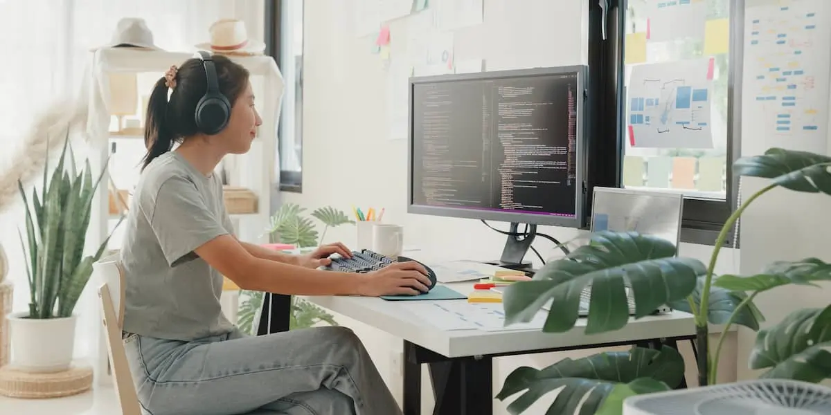 An analyst working on machine learning projects on her computer in a bright home office.