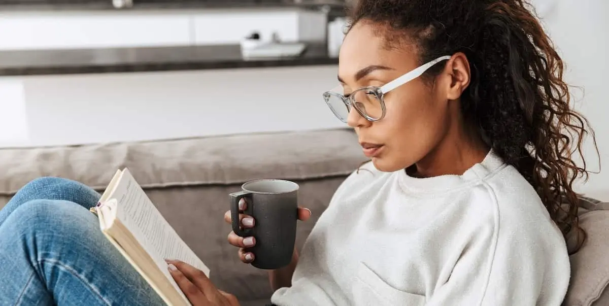 A woman sits on a couch reading product management books.