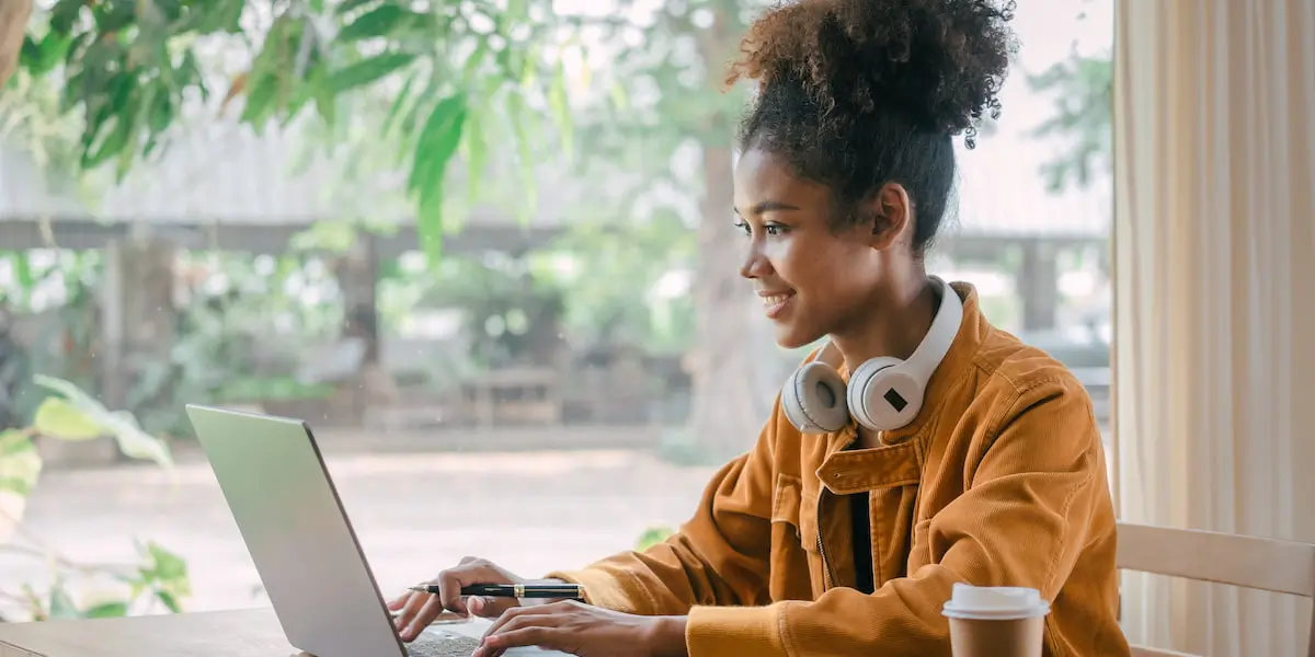 Young woman with hair up smiling while looking at her laptop