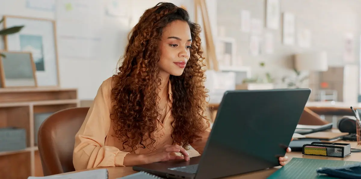 A female product designer sits at her laptop using some of the best product design tools