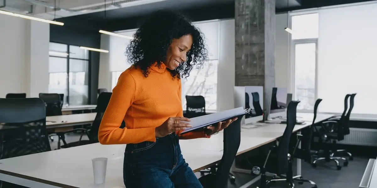 A sustainability analyst stands looking at papers in an office.