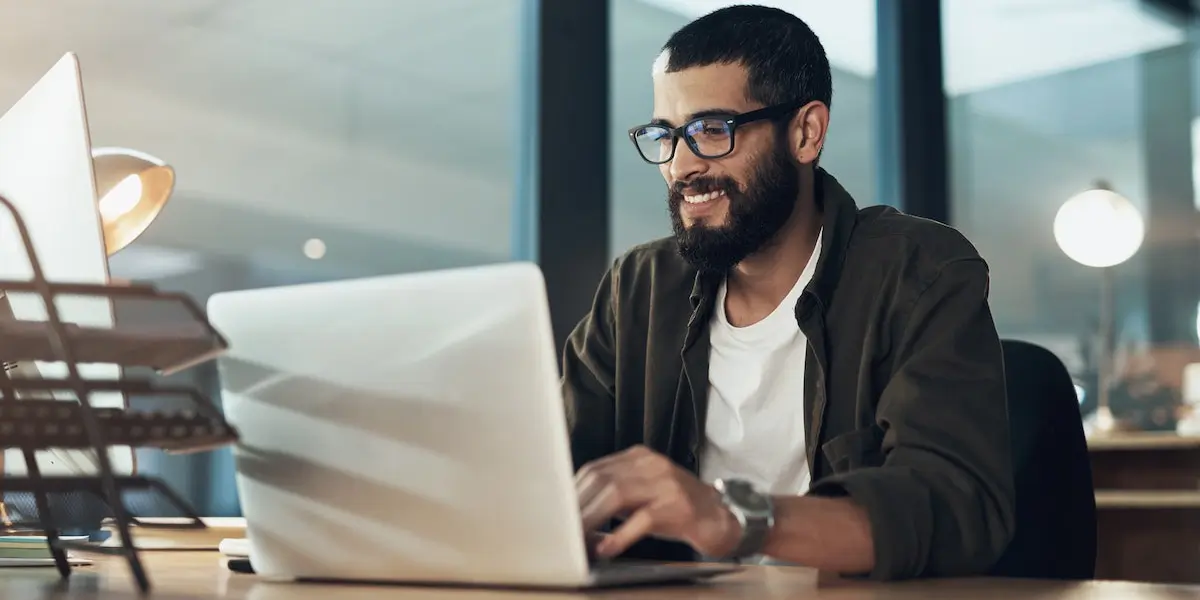 A young man learns how to use ChatGPT on his laptop while at work.